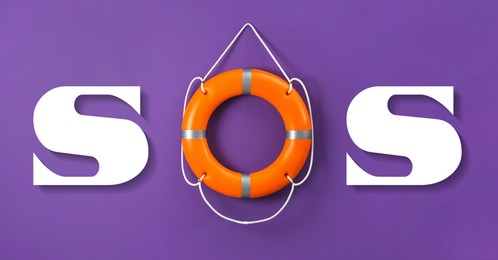 Image of SOS message made from lifebuoy and white letters on violet background
