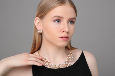 Photo of Beautiful young woman with elegant jewelry on gray background