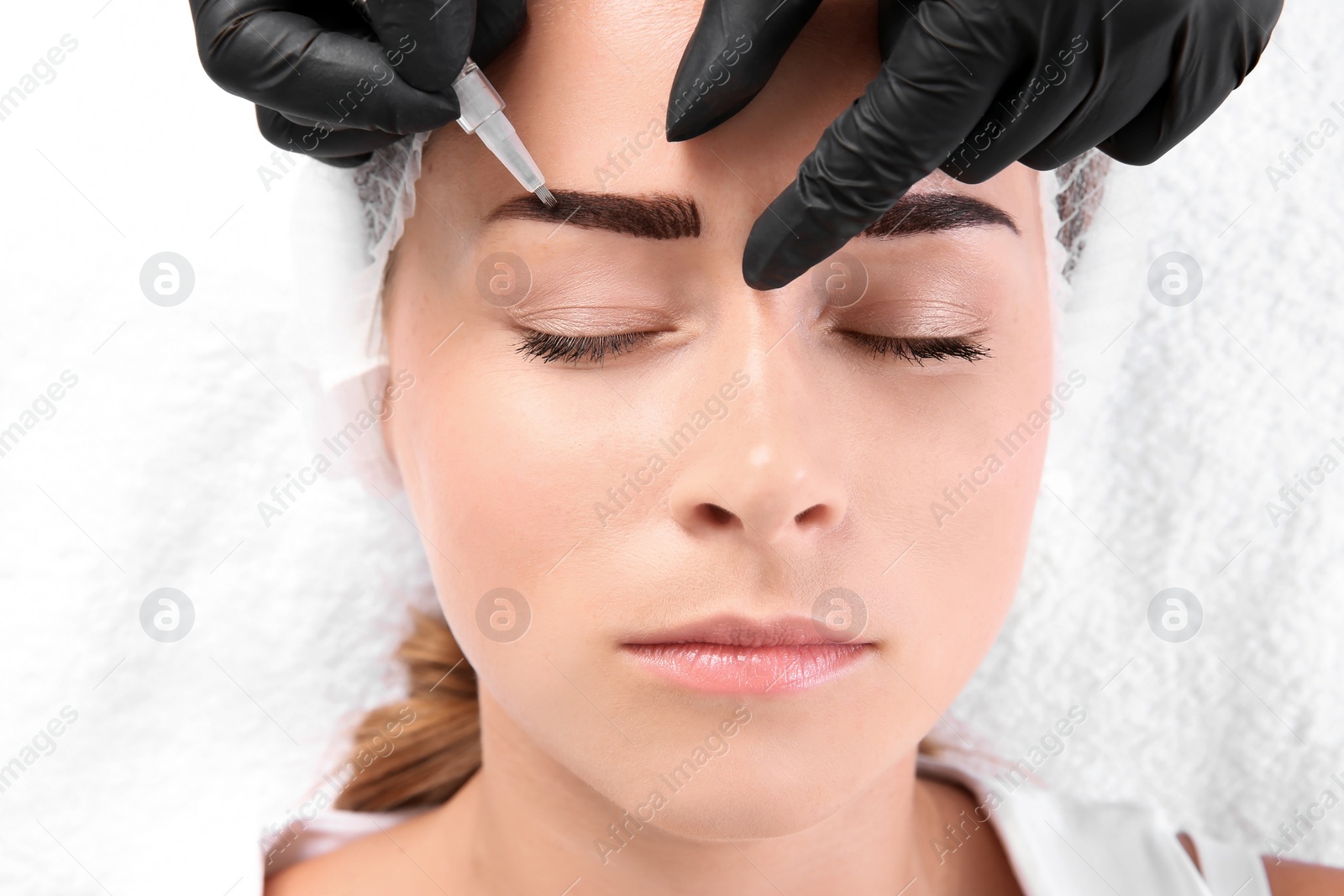 Photo of Young woman undergoing eyebrow correction procedure in salon, top view