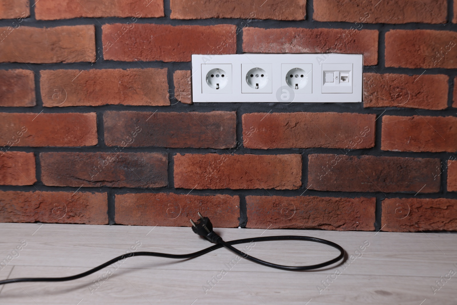 Photo of Electric plug and power sockets on brick wall