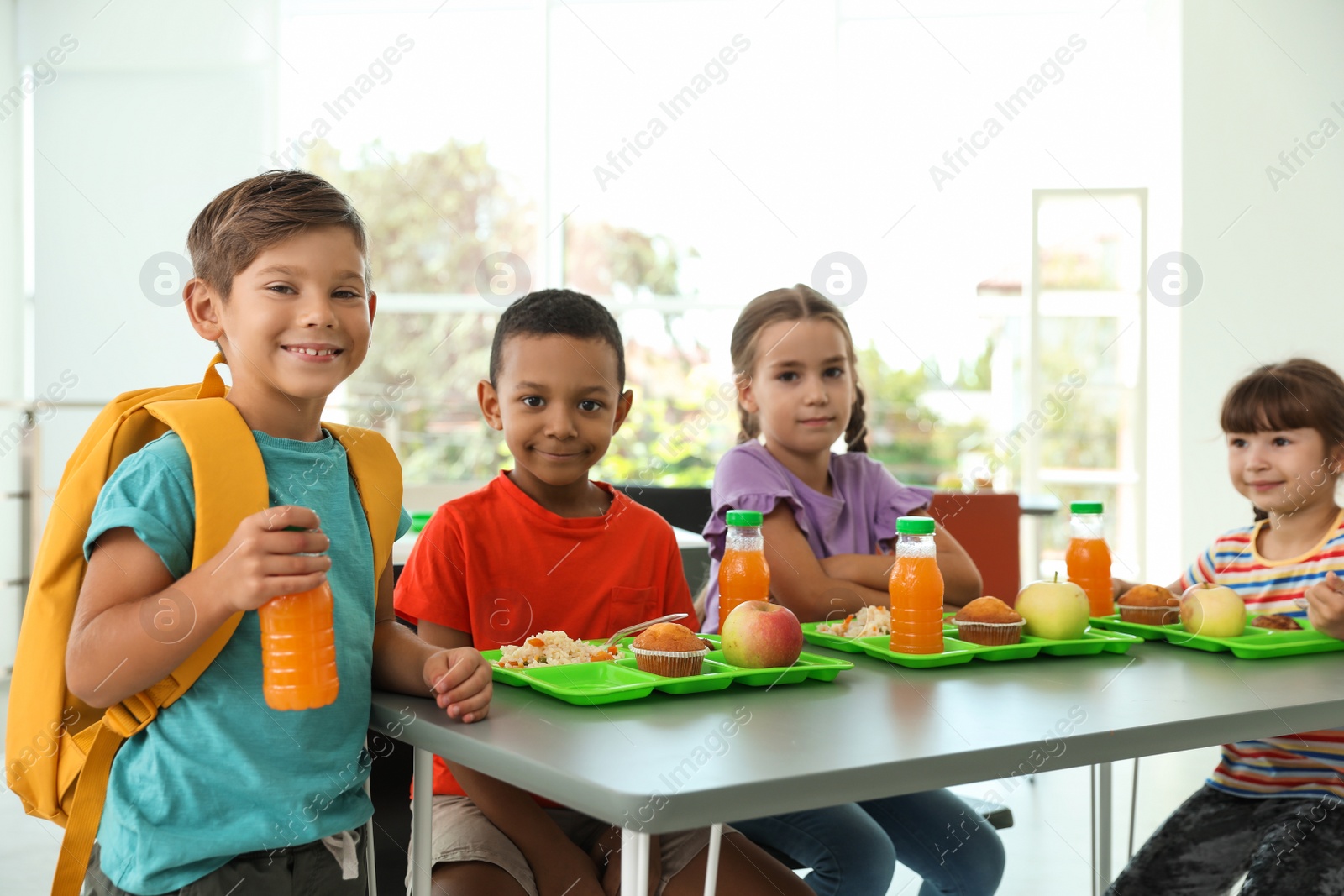 Photo of Children sitting at table and eating healthy food during break at school