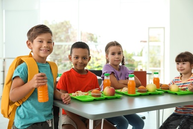 Photo of Children sitting at table and eating healthy food during break at school