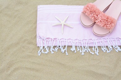 Photo of Blanket, stylish slippers and starfish on sand outdoors, top view with space for text. Beach accessories