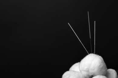 Needles for acupuncture and cotton balls on dark background