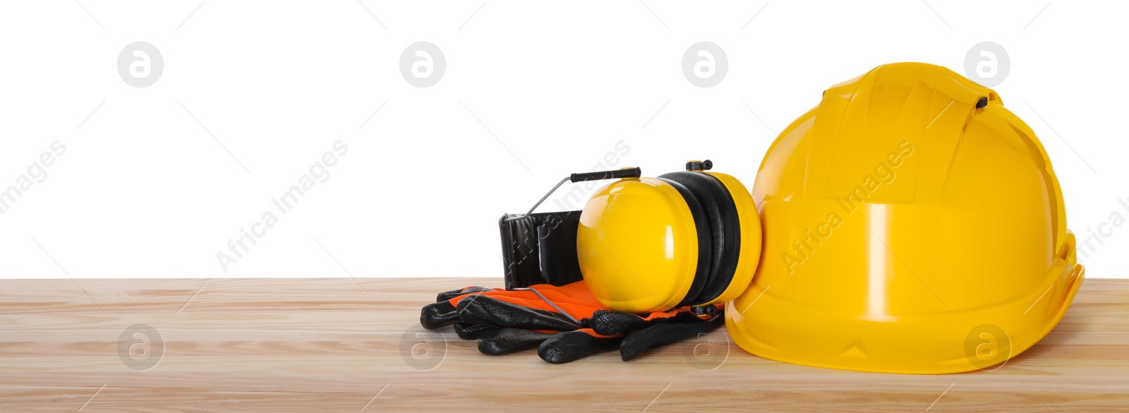Photo of Hard hat, earmuffs and gloves on wooden table against white background. Safety equipment
