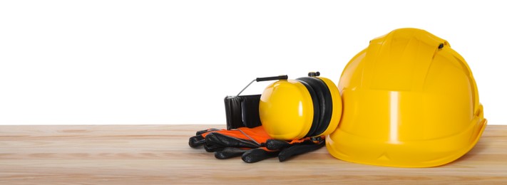 Photo of Hard hat, earmuffs and gloves on wooden table against white background. Safety equipment