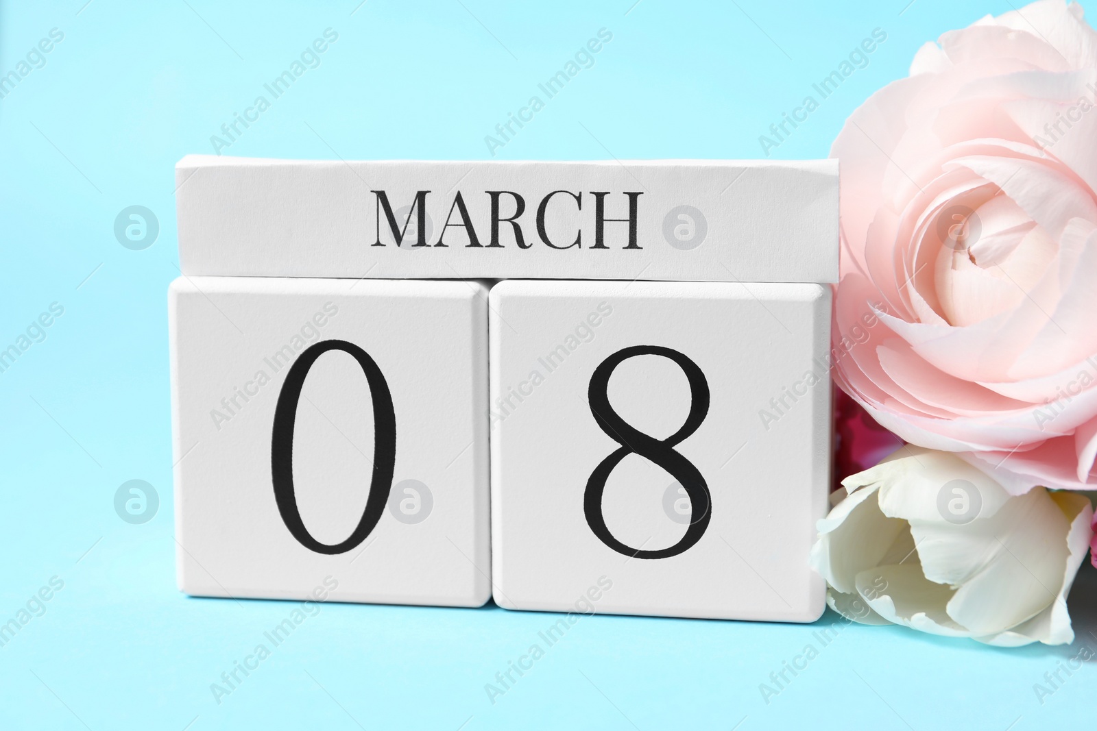 Photo of International Women's day - 8th of March. Wooden block calendar and beautiful flowers on light blue background