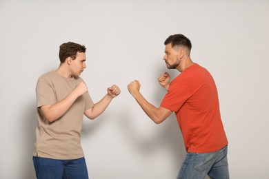 Photo of Two emotional men fighting on beige background