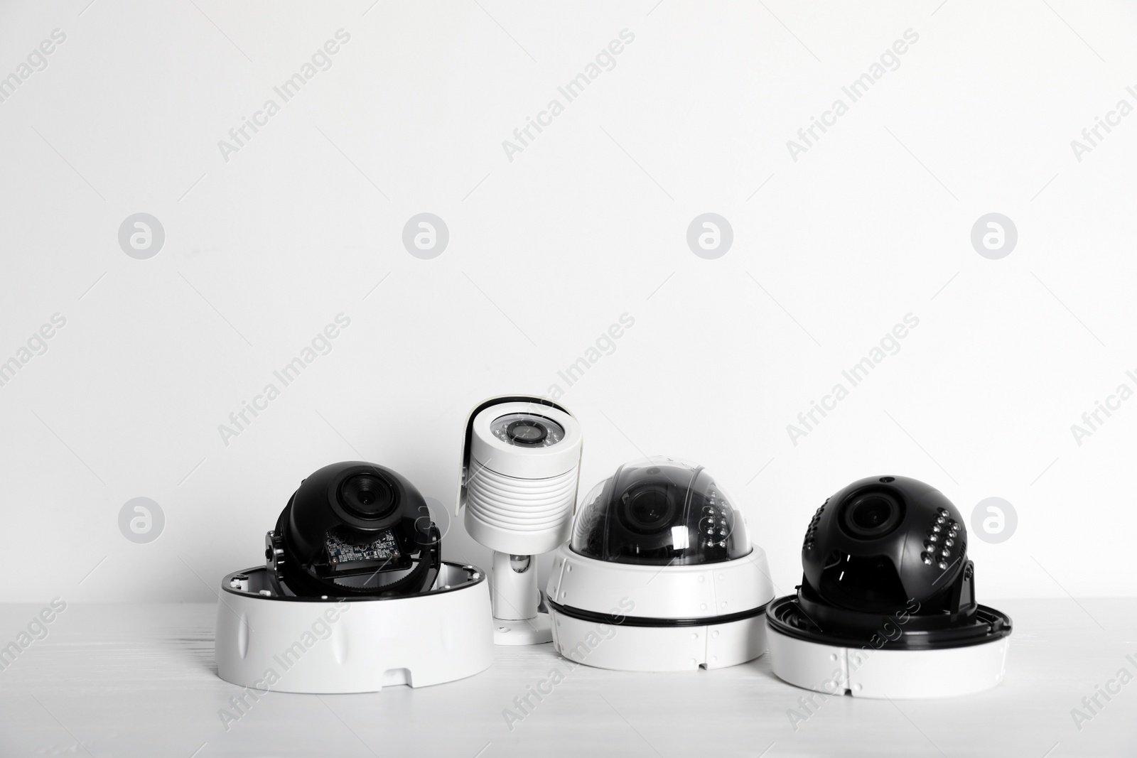 Photo of Modern CCTV cameras on table against light background. Home alarm system