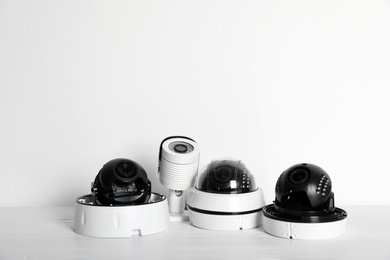 Photo of Modern CCTV cameras on table against light background. Home alarm system