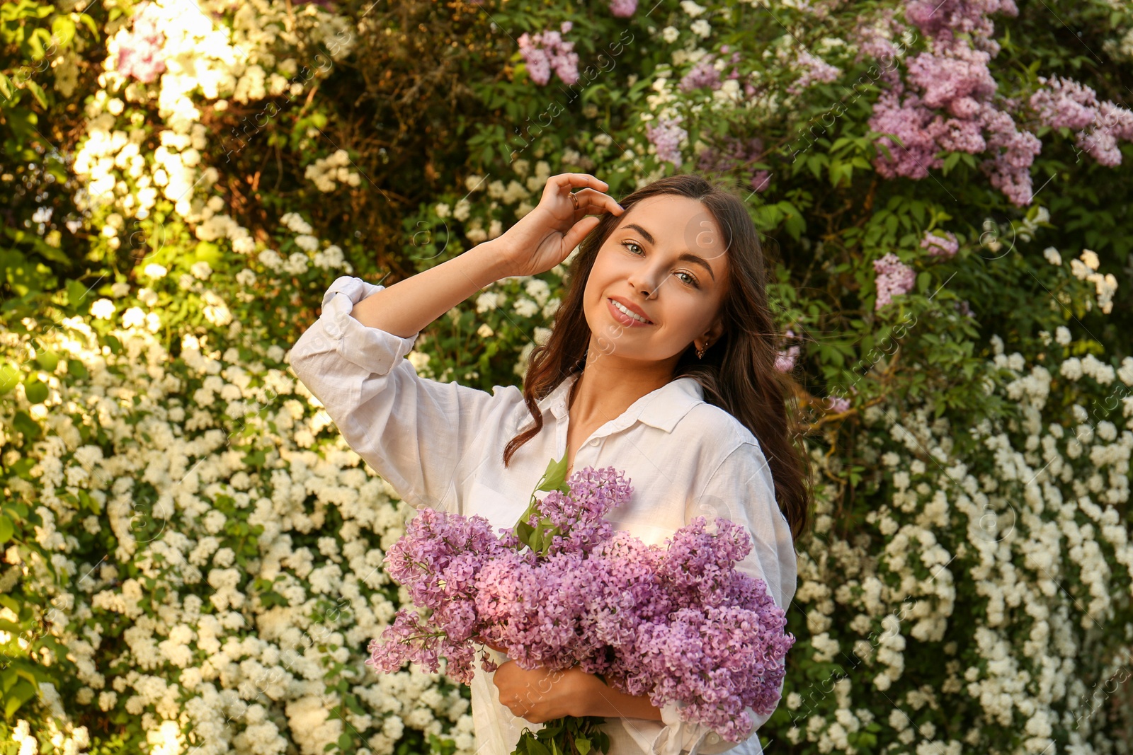 Photo of Attractive young woman with lilac flowers outdoors