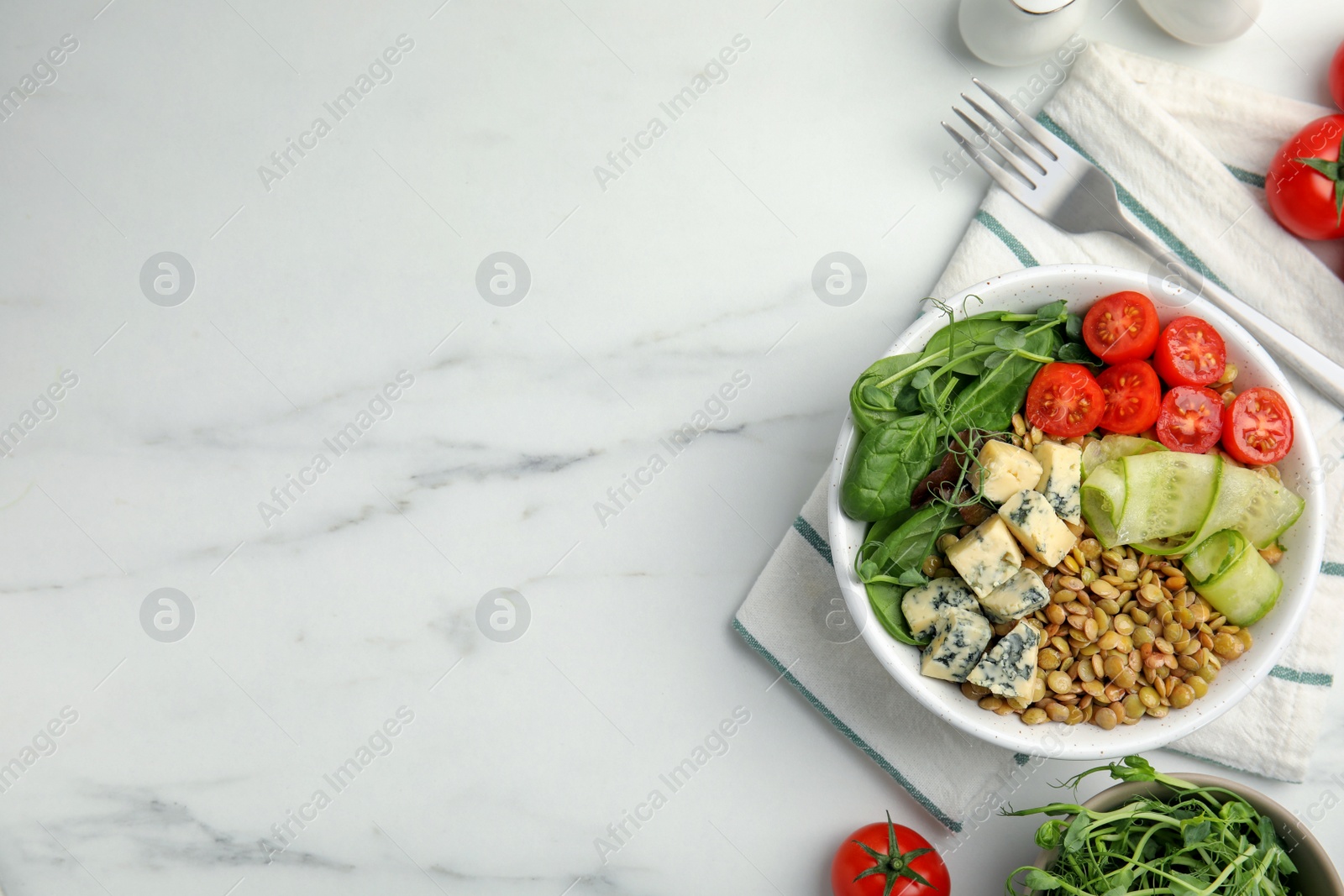 Photo of Delicious lentil bowl with blue cheese, tomatoes and cucumber on white marble table, flat lay. Space for text