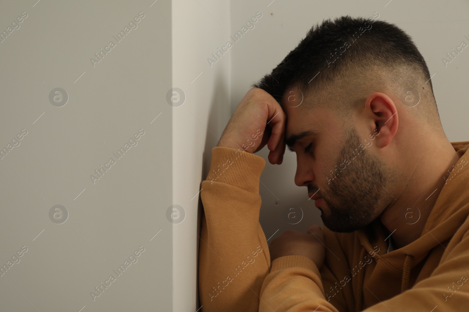 Photo of Sad young man at home. Space for text