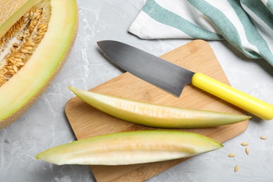 Photo of Slices of delicious ripe melon and knife on grey marble table, flat lay