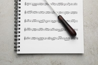 Photo of Conductor's baton and sheet music book on grey background