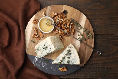 Photo of Tasty blue cheese with thyme, honey and walnuts on wooden table, top view
