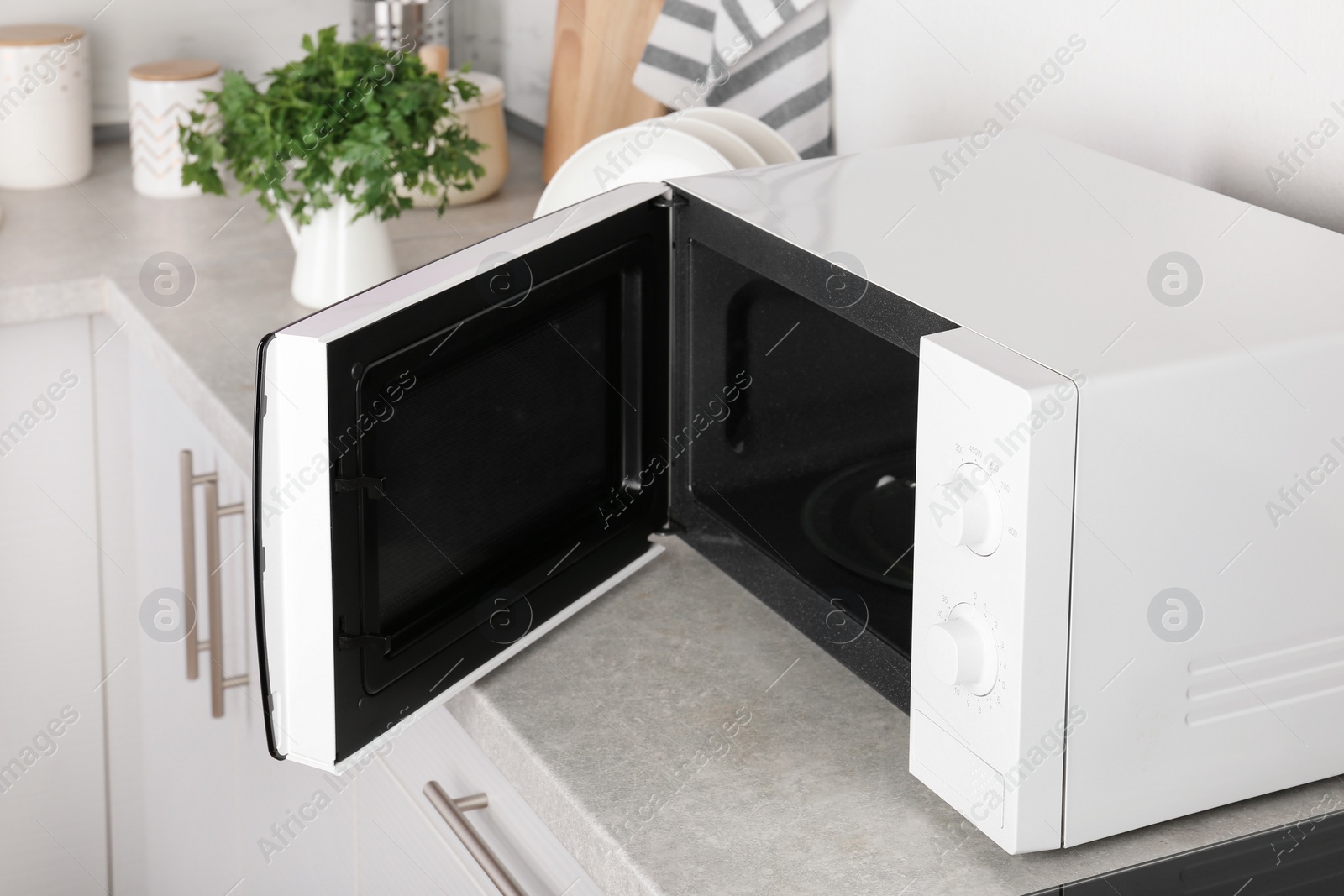 Photo of Open modern microwave oven on table in kitchen