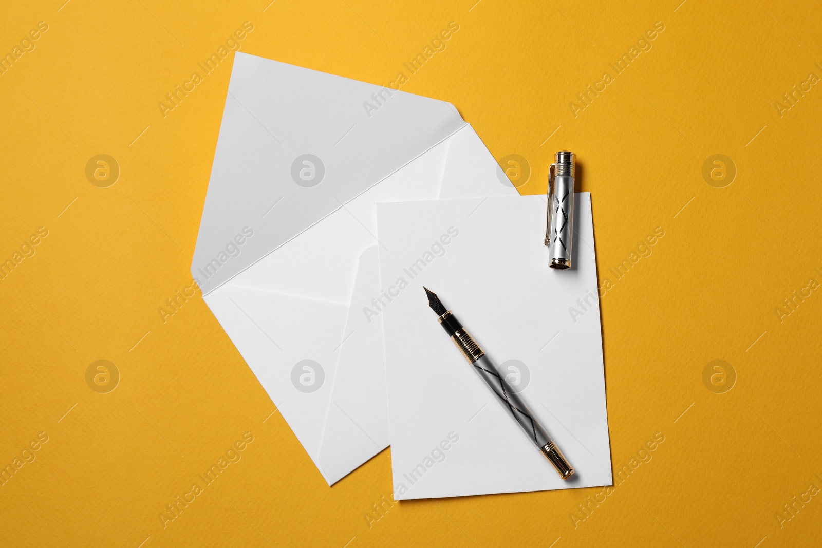 Photo of Blank sheet of paper, letter envelope and pen on orange background, top view