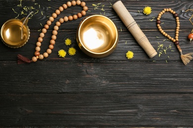 Flat lay composition with golden singing bowl on black wooden table, space for text. Sound healing