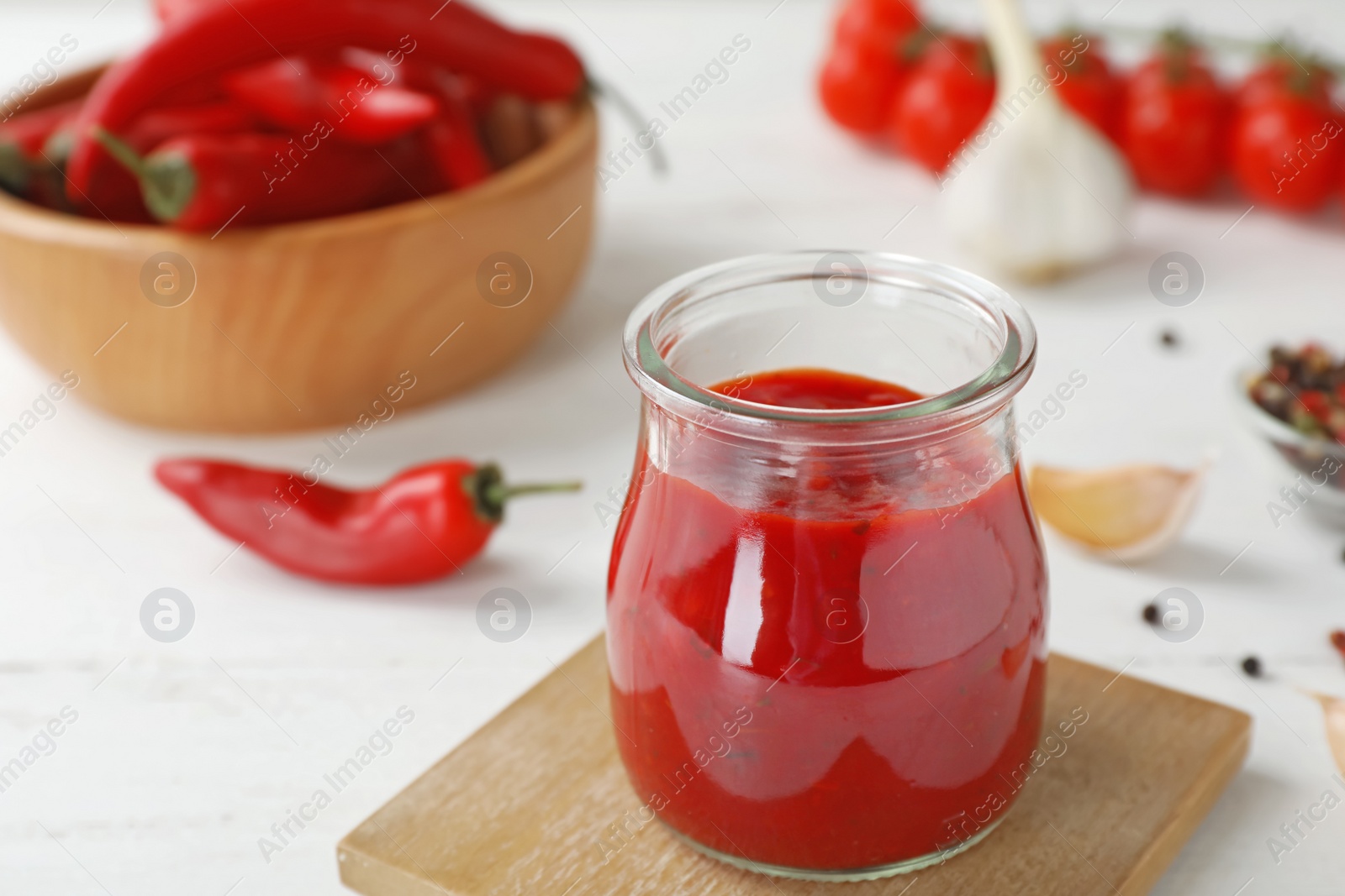 Photo of Jar with spicy chili sauce on light table