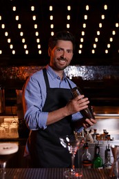 Photo of Bartender with shaker preparing fresh alcoholic cocktail in bar