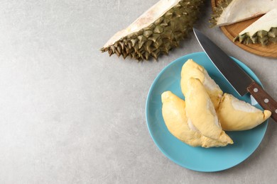 Photo of Plate with fresh ripe durian and knife on grey table, flat lay. Space for text