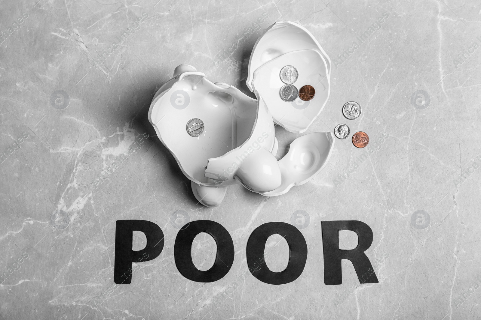 Photo of Broken piggy bank with coins and word POOR on grey background, top view