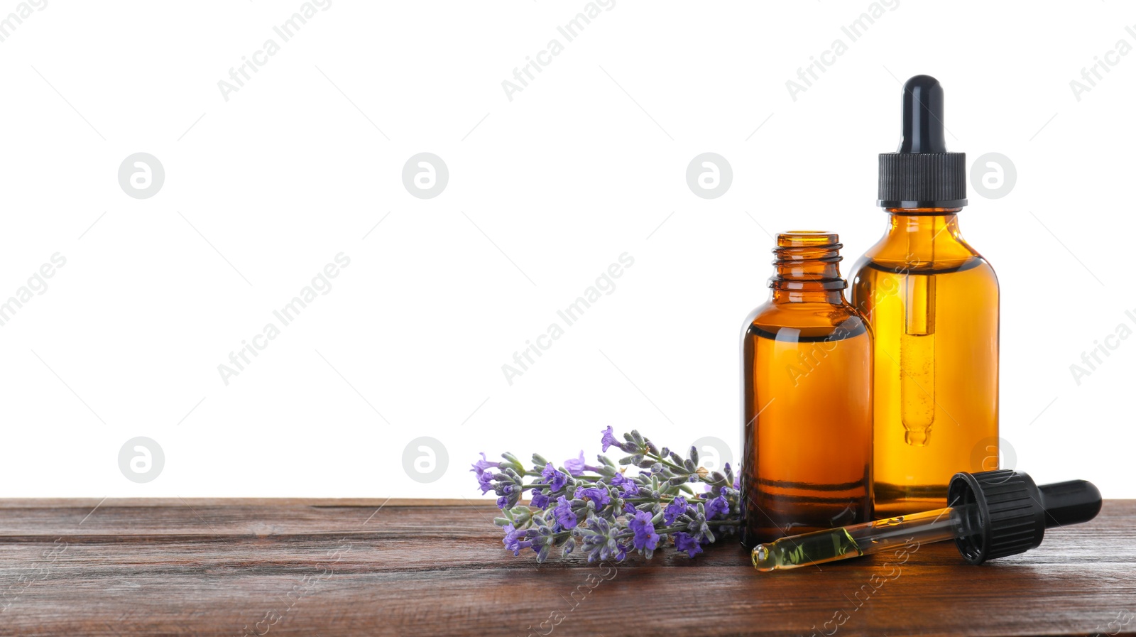 Photo of Bottles of essential oil and lavender flowers on wooden table against white background