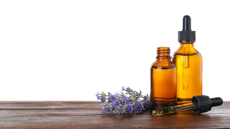 Photo of Bottles of essential oil and lavender flowers on wooden table against white background