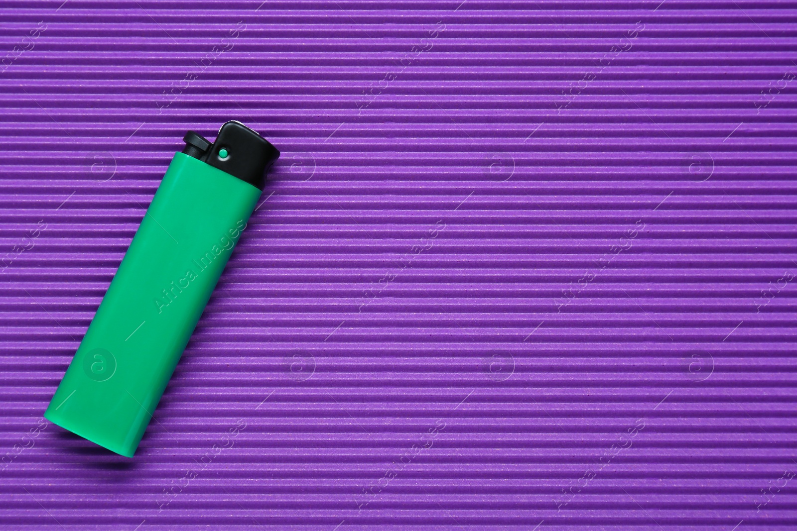 Photo of Stylish small pocket lighter on purple corrugated fiberboard, top view. Space for text