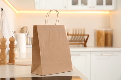 Paper shopping bag on white countertop in kitchen. Space for text