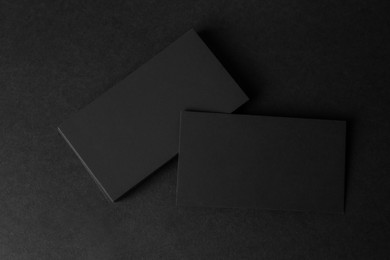 Blank business cards on black background, flat lay. Mockup for design