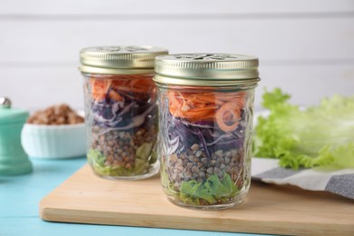 Glass jars with healthy meal on light blue wooden table