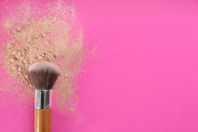 Makeup brush and scattered face powder on bright pink background, top view. Space for text