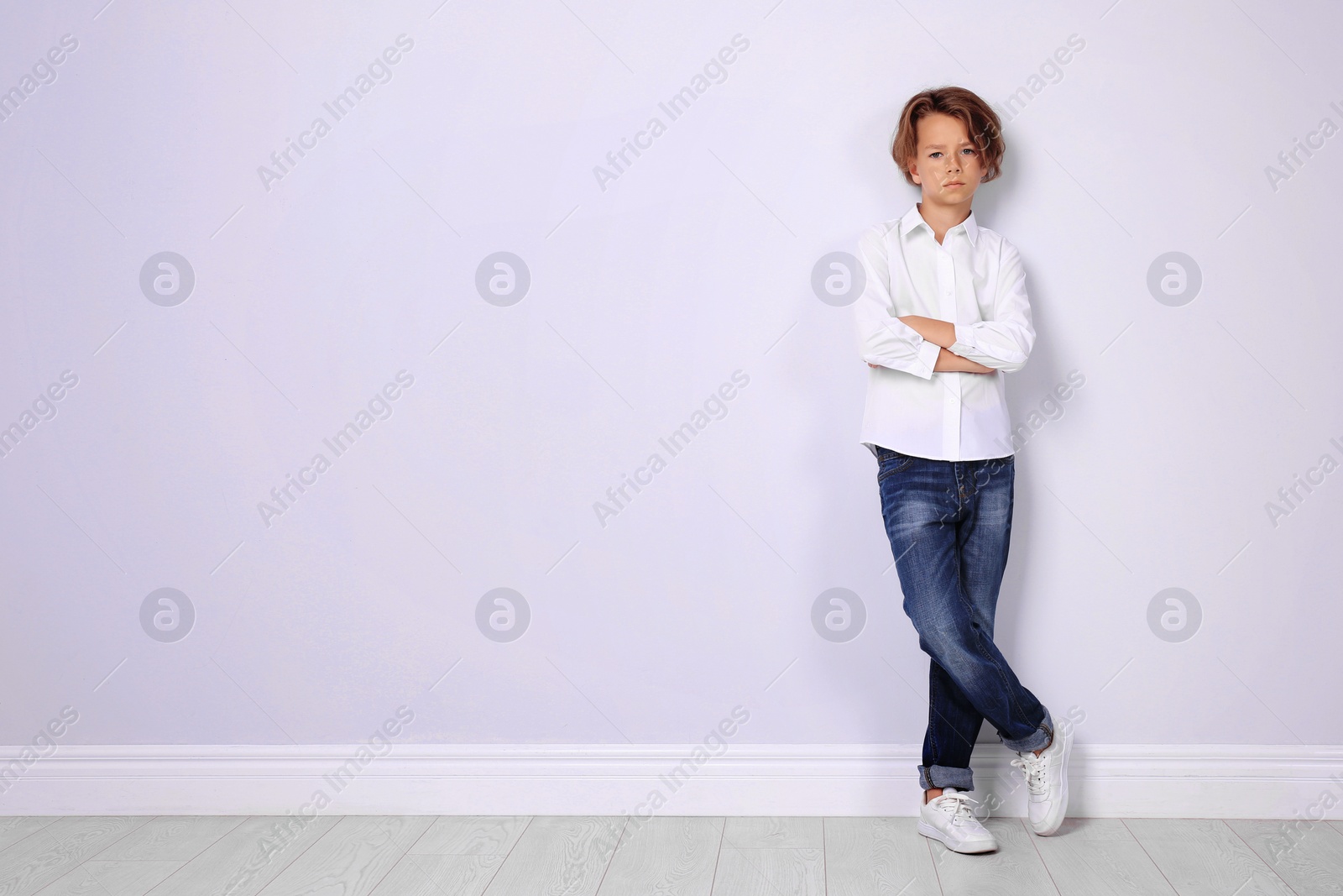 Photo of Cute little boy in casual outfit near white wall. Space for text