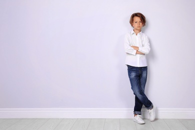 Photo of Cute little boy in casual outfit near white wall. Space for text