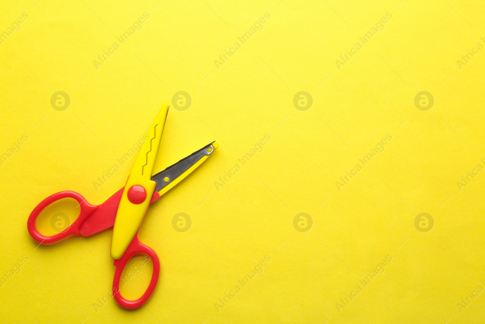 Photo of Decorative edge scissors on color background, top view. Space for text