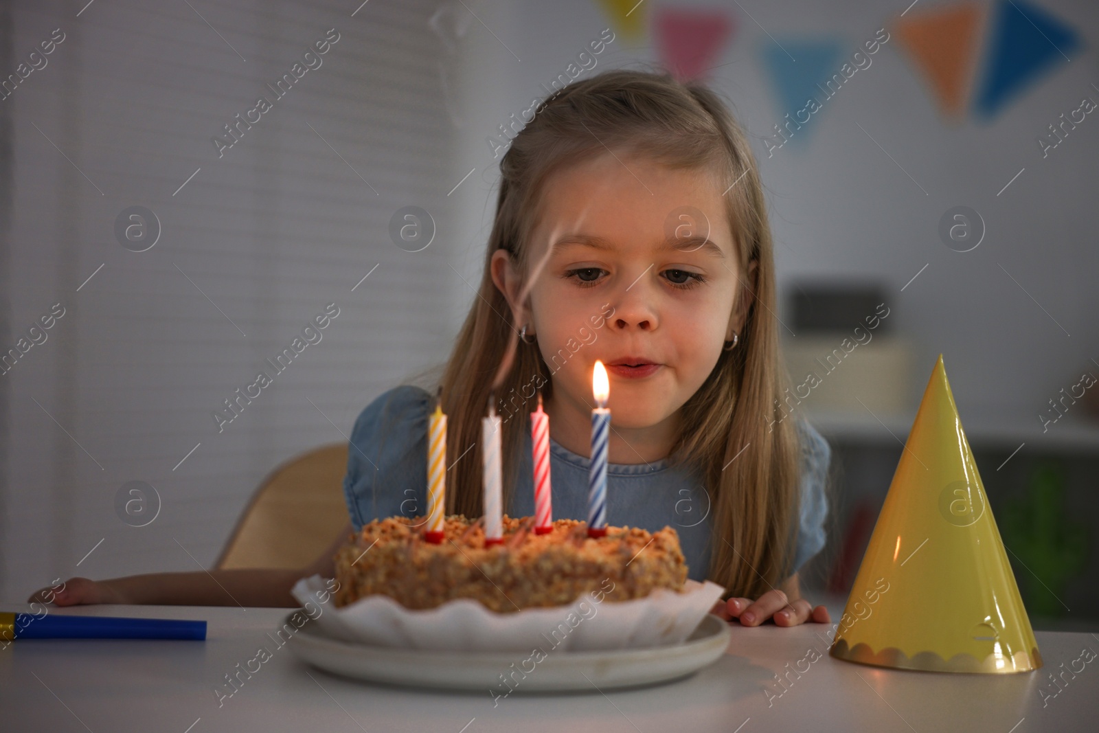 Photo of Cute girl with birthday cake at table indoors