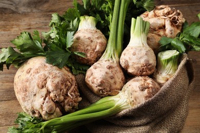 Photo of Fresh raw celery roots and sack on wooden table