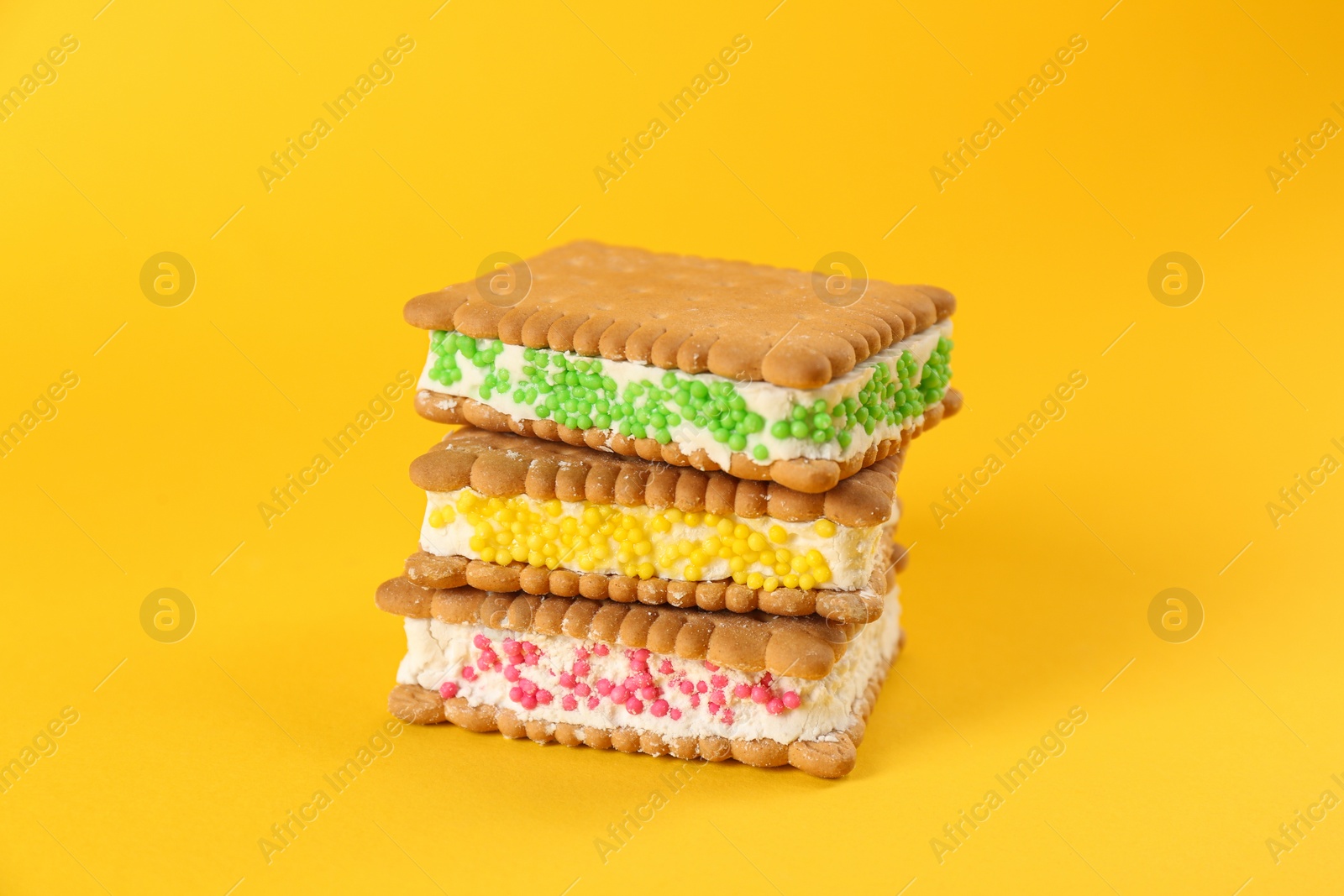 Photo of Sweet delicious ice cream cookie sandwiches on yellow background