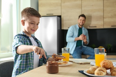 Photo of Dad and son having breakfast together in kitchen