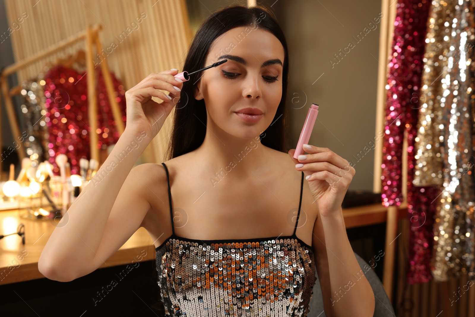 Photo of Beautiful young woman applying mascara in dressing room