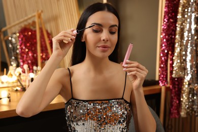 Photo of Beautiful young woman applying mascara in dressing room