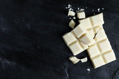 Photo of Delicious white chocolate on black table, flat lay. Space for text