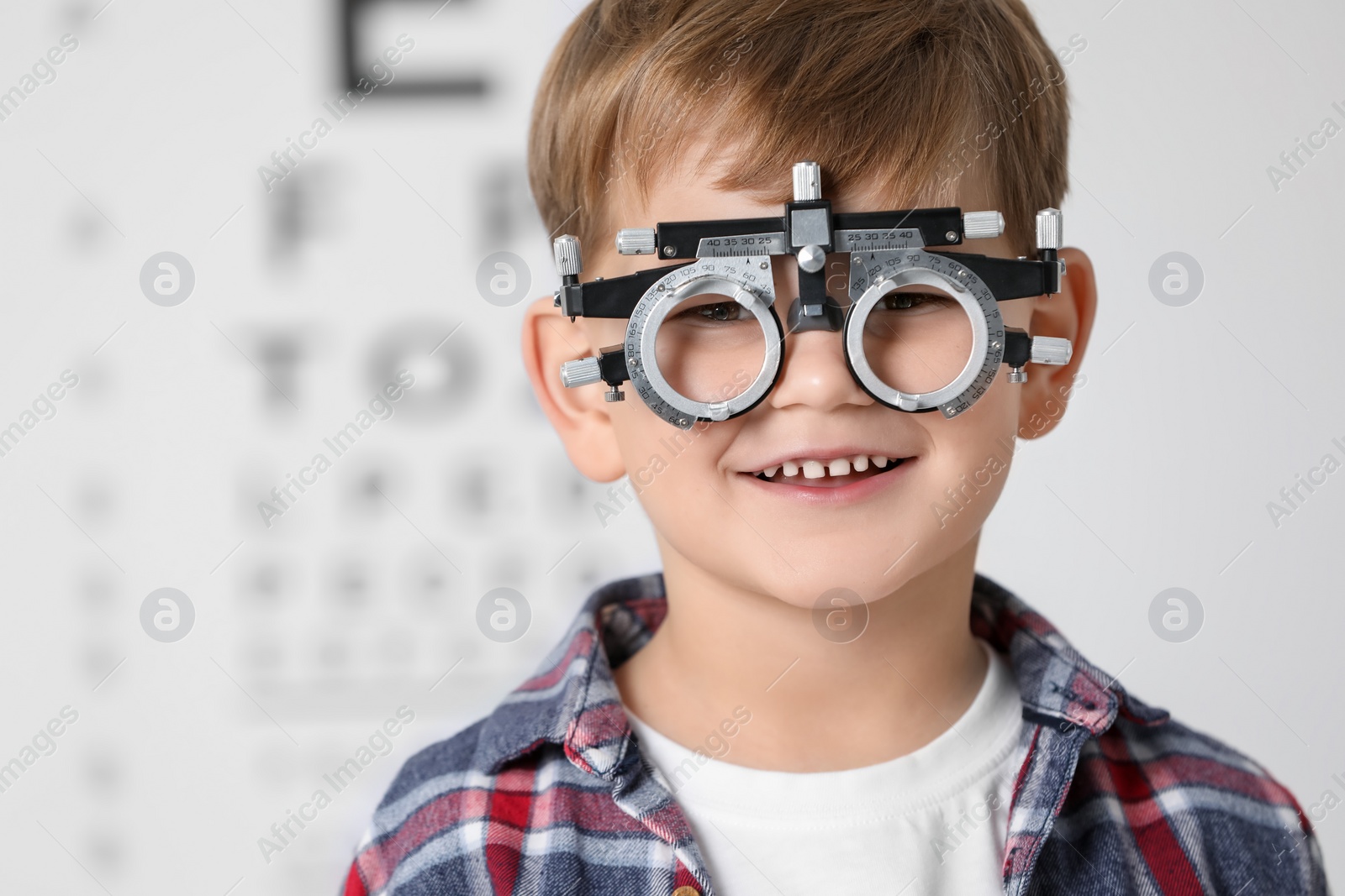 Photo of Little boy with trial frame against vision test chart