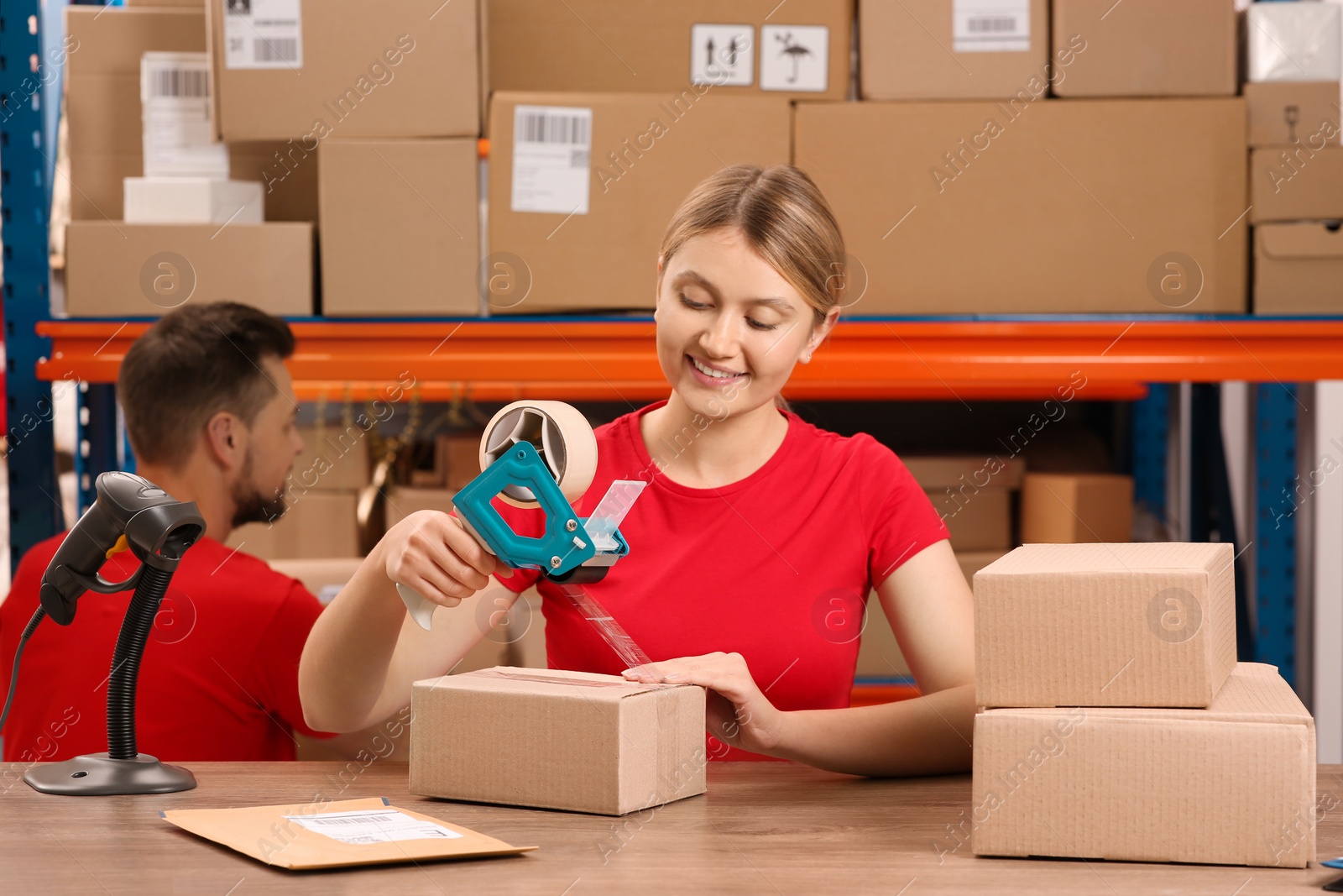 Photo of Post office worker packing parcel at counter indoors