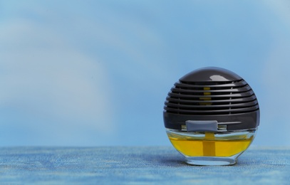 Photo of Car air freshener on table against color background