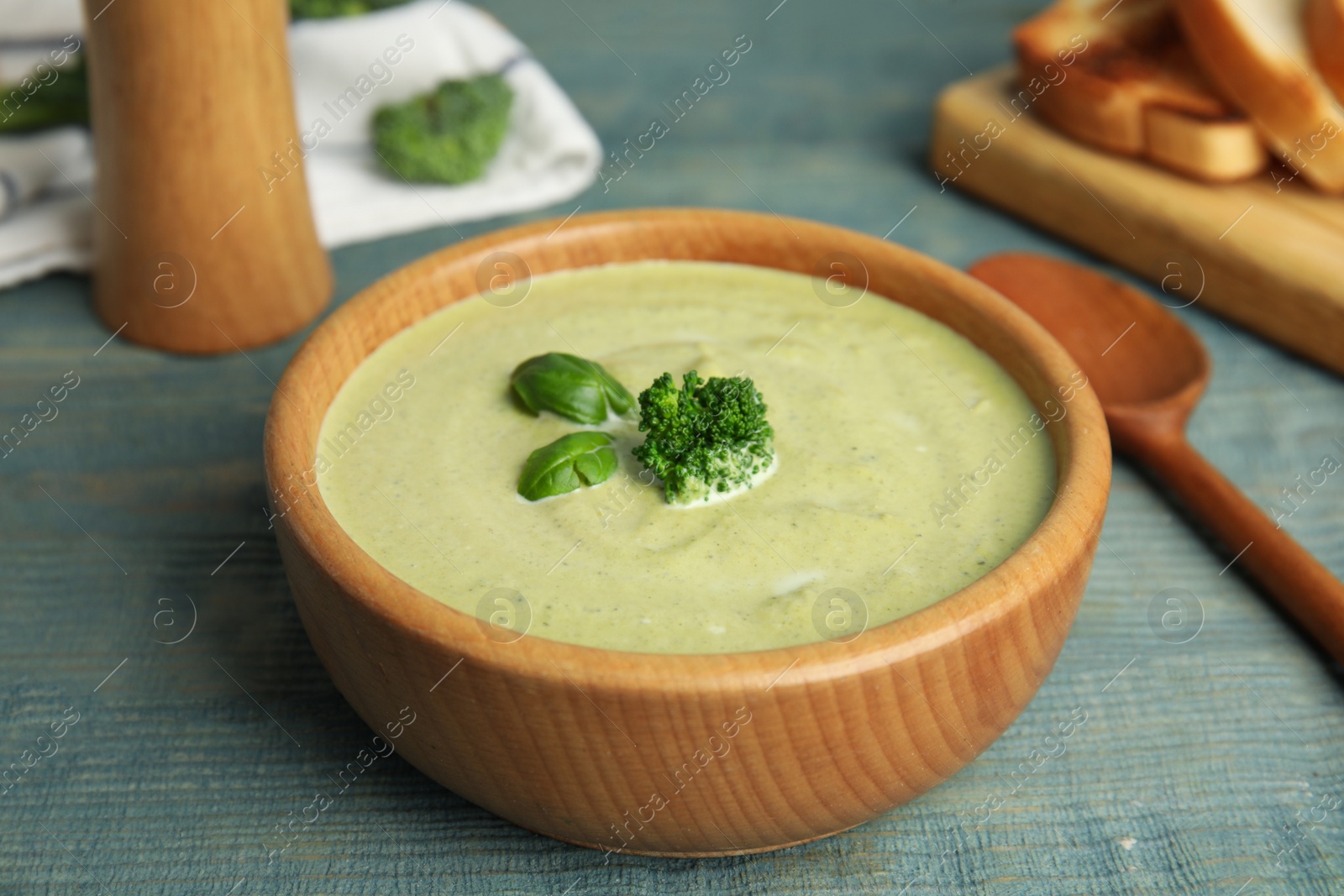 Photo of Delicious broccoli cream soup served on blue wooden table