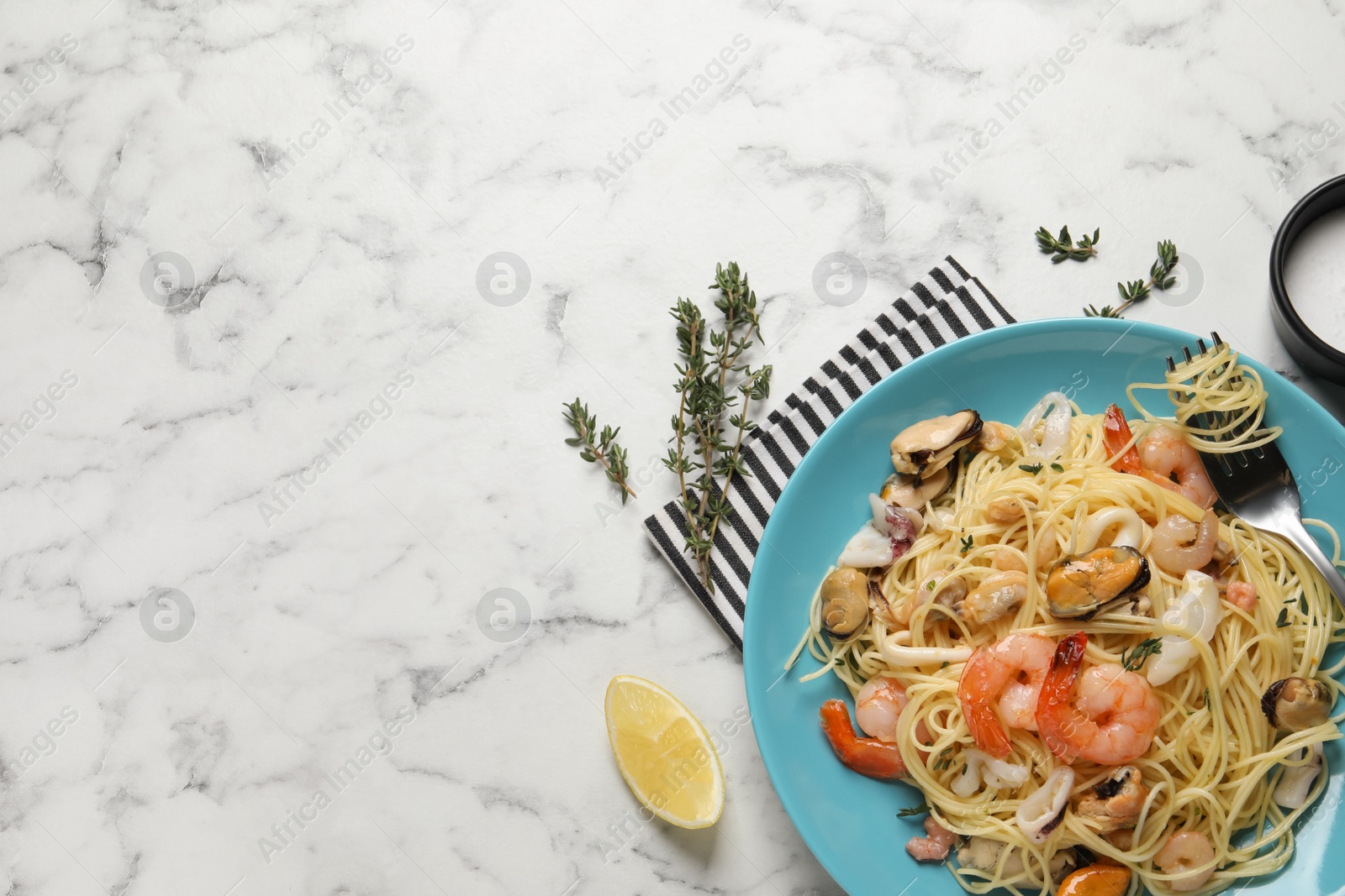 Photo of Delicious pasta with sea food served on white marble table, flat lay. Space for text