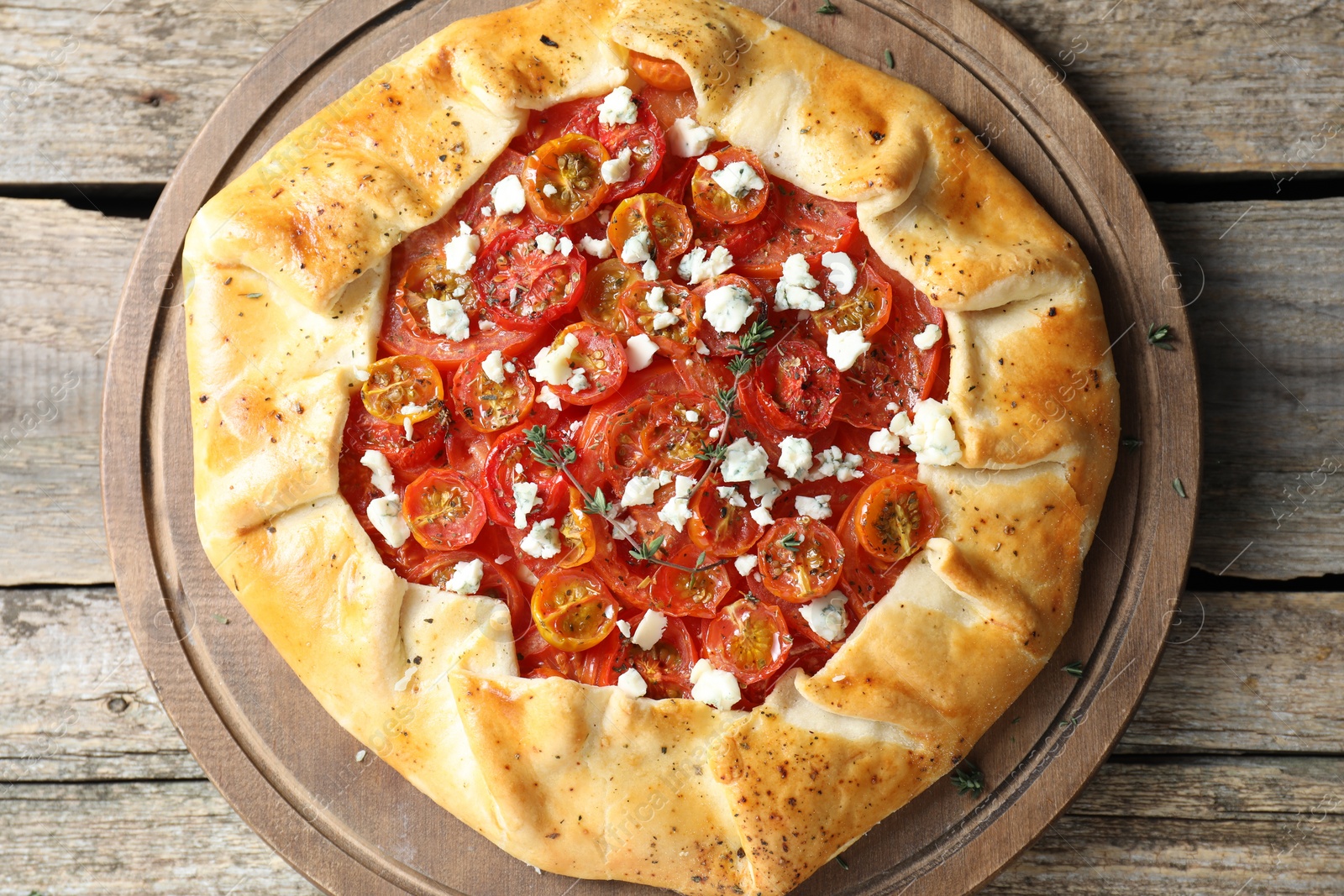 Photo of Tasty galette with tomato, thyme and cheese (Caprese galette) on wooden table, top view